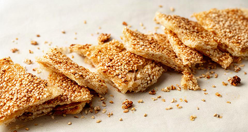 Snack croccante al sesamo spezzato in porzioni su carta alimentare